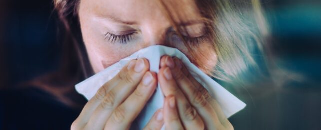 Woman Sneezes Into Tissue