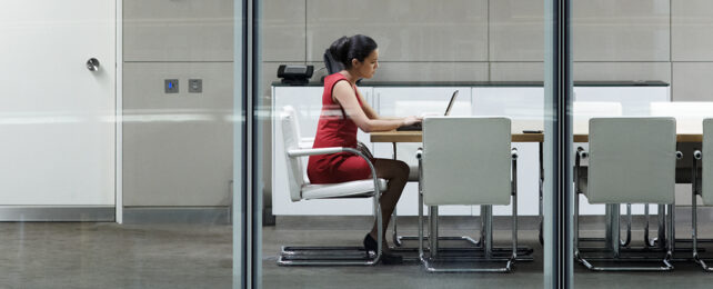 woman in a red dress sitting in an office chair at a table