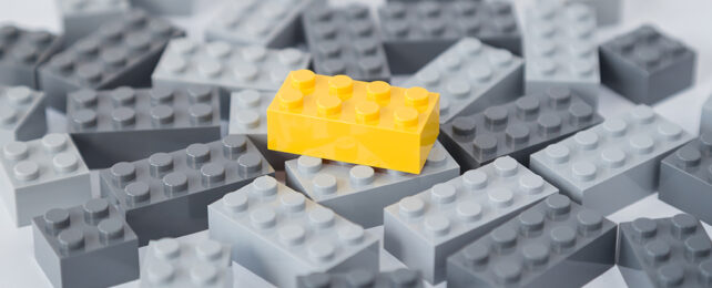 yellow lego brick on pile of grey bricks