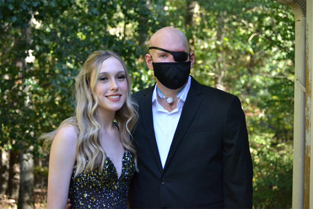 Image of patient standing with family with mask and eye patch.
