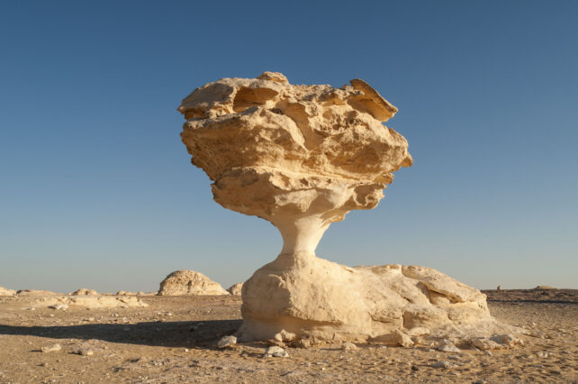 Mushroom shaped rock formation towering over a desert landscape