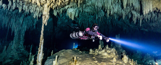 diver swimming through underwater cave