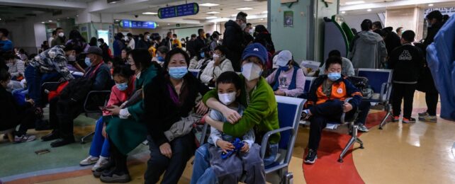 patients sitting in a hospital waiting area wearing masks