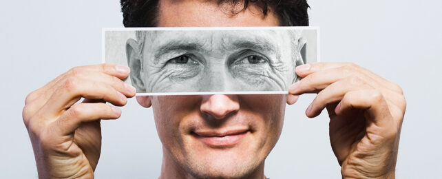 younger man holding image of older man's eyes over his own