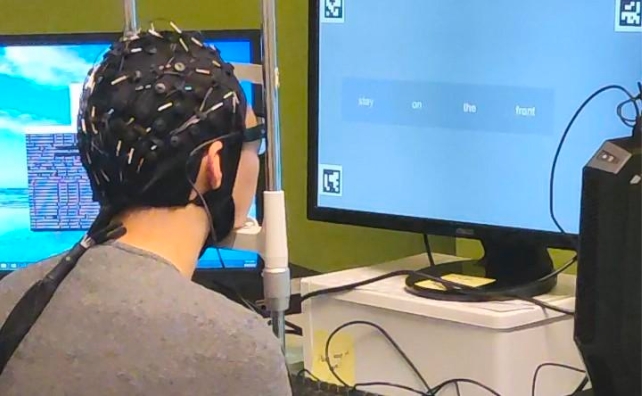 A person wearing a cap with sensors looking at a monitor