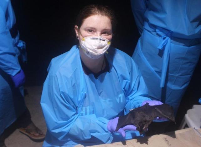 researcher poses with vampire bat during field research