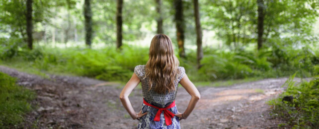 women standing between two paths with hands on hips