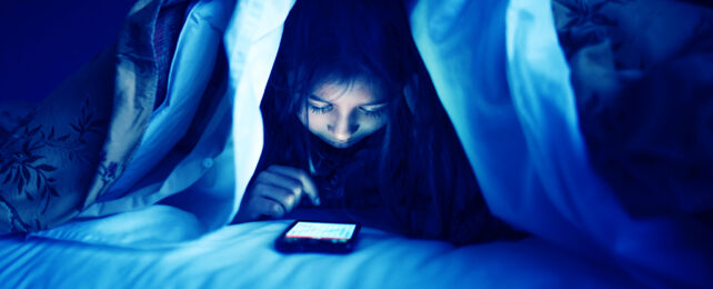 girl under a blanket reading her phone