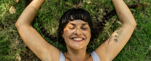 woman laying on the grass smiling with her eyes closed