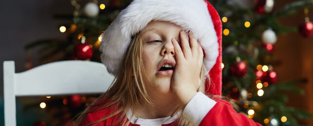 kid in santa hat with a hand on her face