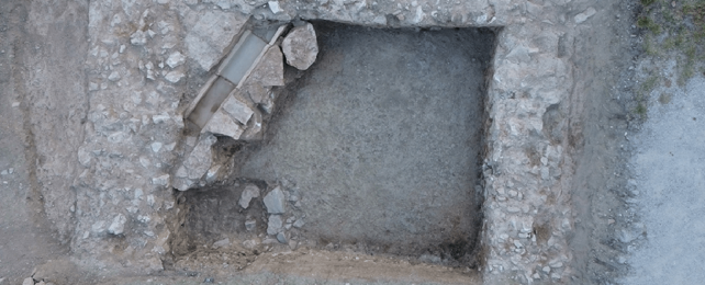 Aerial view of archeology excavation pit revealing three walls.