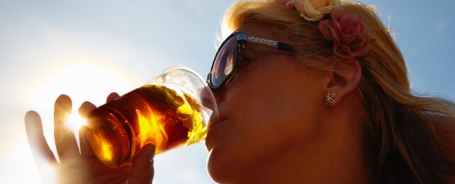 Woman Drinks Beverage In Sunlight