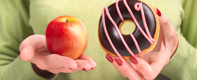 person holding an apple and doughnut in each hand