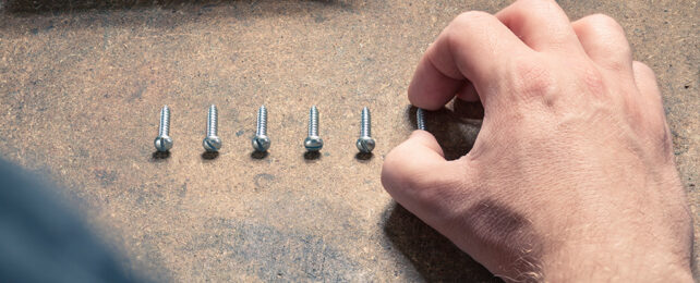 man lining up screws