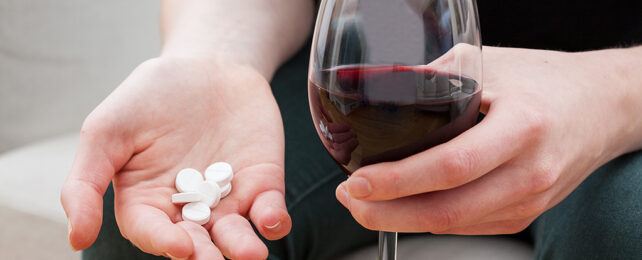 woman holding wine and pills