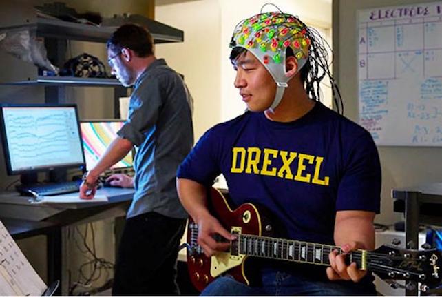 researcher playing guitar while wearing EEG electrode cap