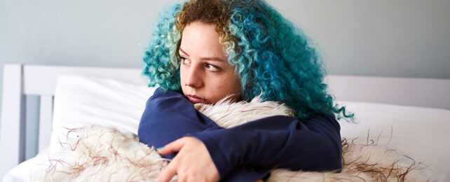blue haired girl sitting on bed