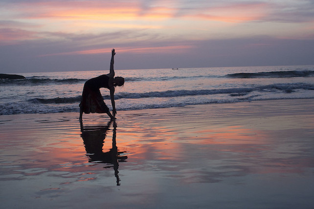 silhouette of person doing yoga on beach at sunset