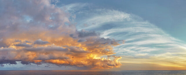 Different types of clouds over an ocean at sunset