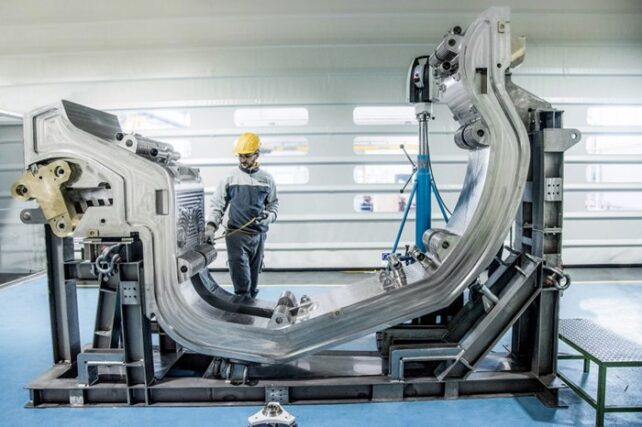 Technician standing next to U-shaped metal construction.