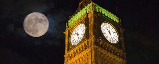 The moon next to a clock tower