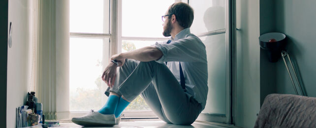 man sitting near window looking outside