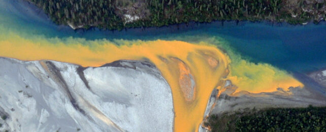Cloudy orange runoff oozing into blue river