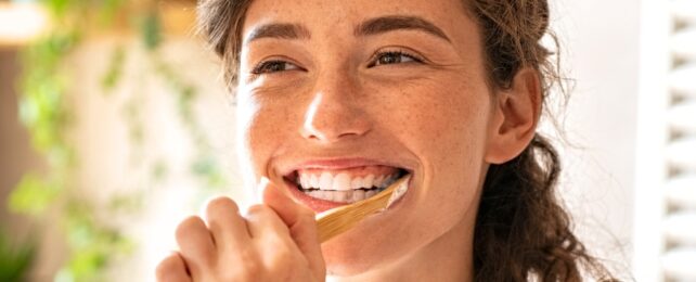 A smiling person brushing their teeth