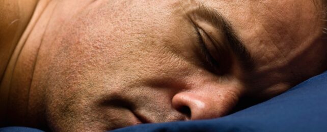 man sleeps on blue pillow