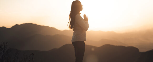 silouette of woman meditating against sunset