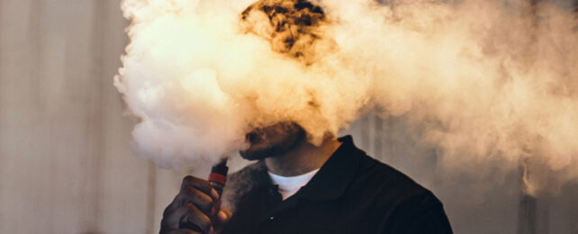 Vaping man with head in the cloud of vape smoke