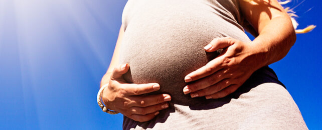 pregnant belly with sun in the background