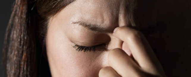 dark haired women holding face frowning