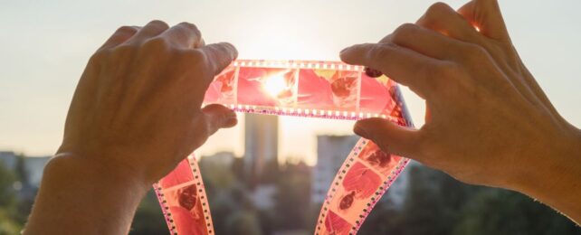 Hands holding old film strip to the light