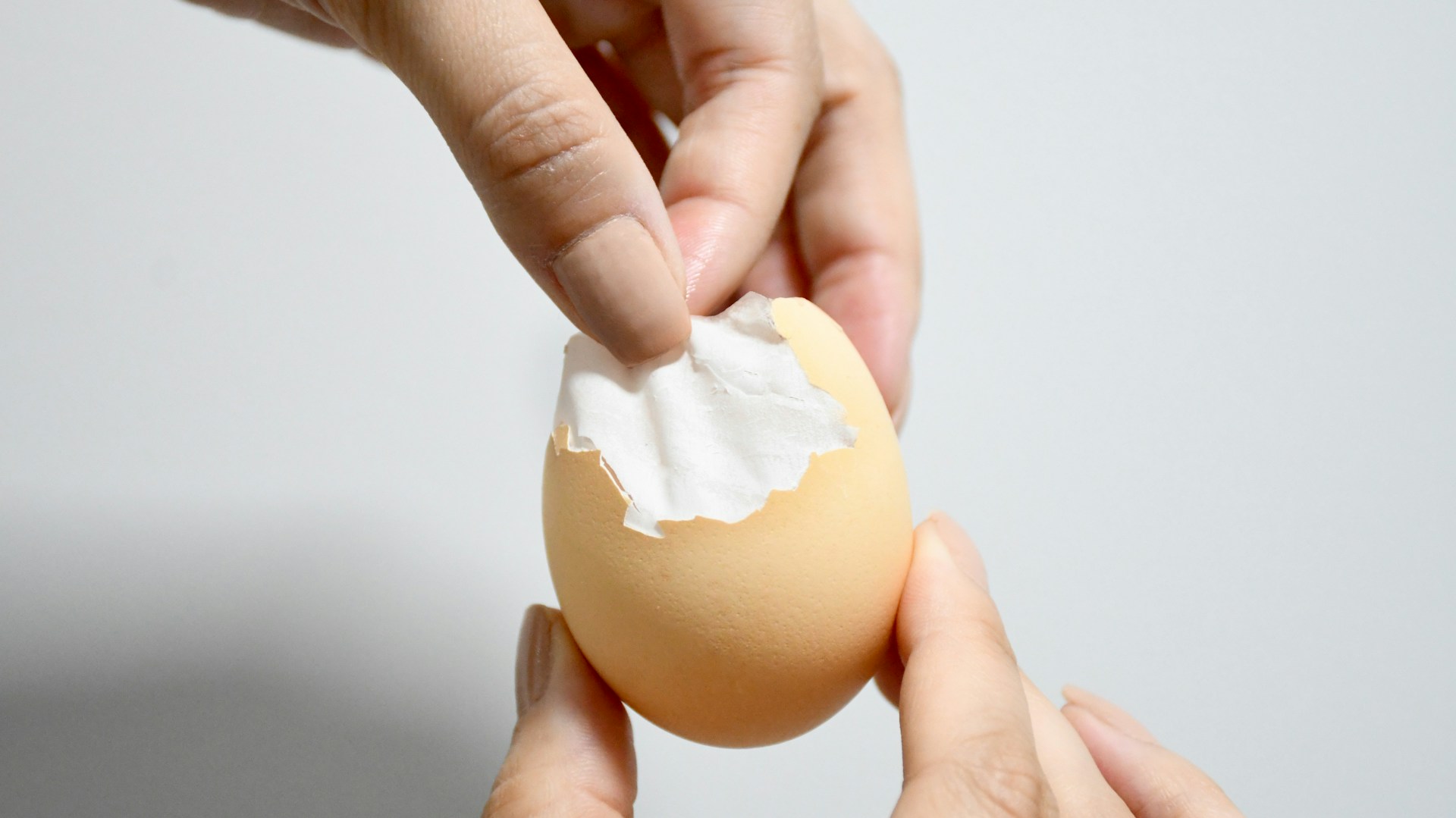 Hands peeling a boiled egg