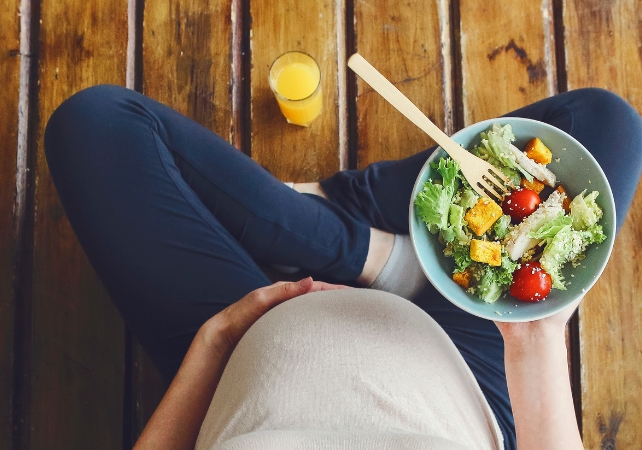 pregnant woman holding a bowl of salad