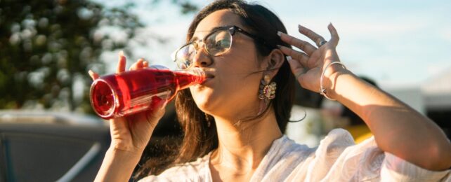 Woman drinking a red beverage from a bottle