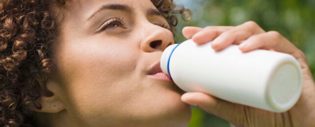 woman drinking from a white bottle