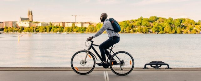 Businessman cycling on promenade near sea against sky