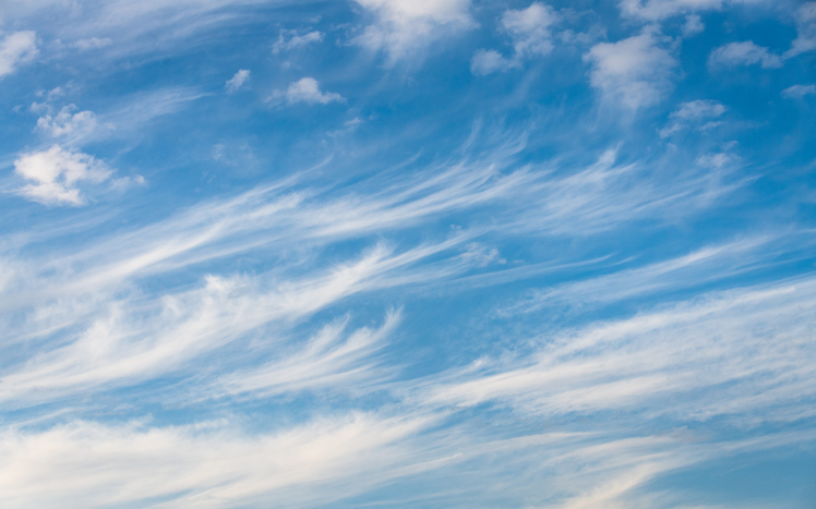 Wispy white clouds covering most of the blue sky