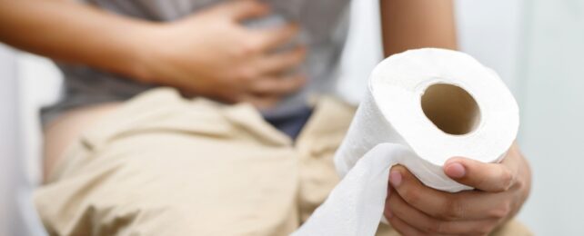 Person holding stomach on toilet