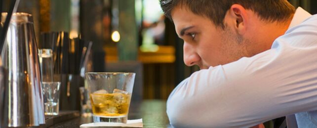 Man staring at a glass of alcohol