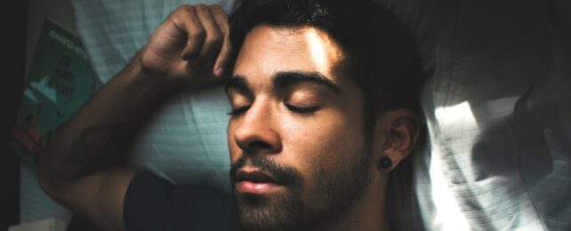 man sleeping in bed with a book