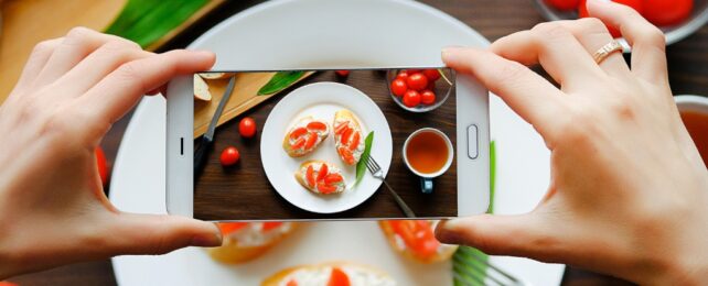 hands holding a phone taking photos of food