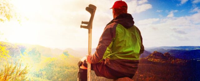 person with crutches on a mountain