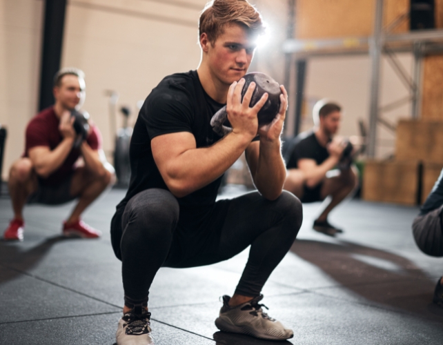 man squatting with weights
