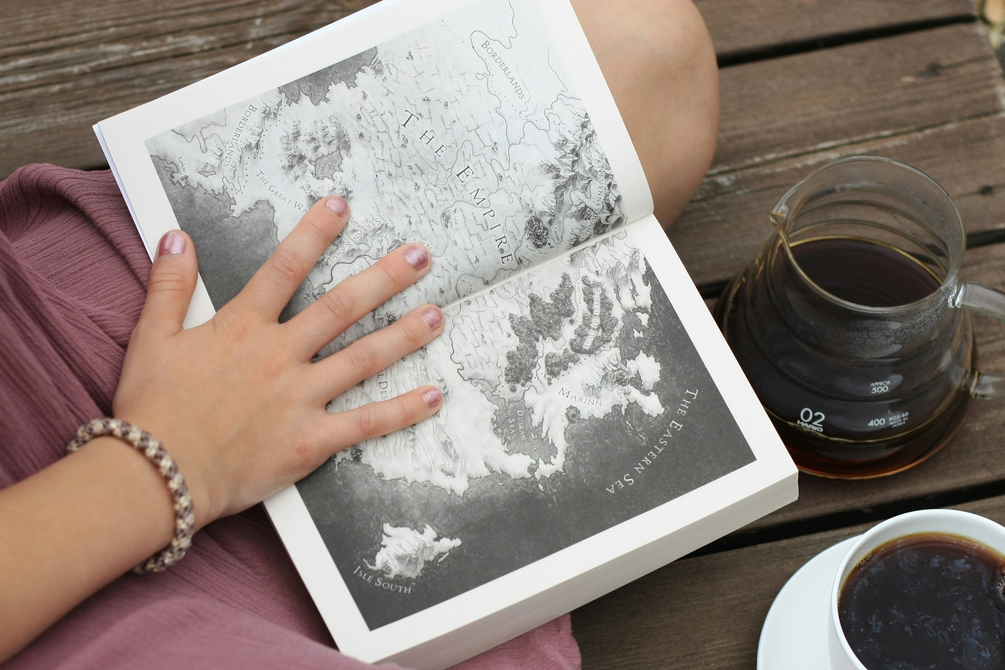 Fantasy book in the lap of a woman held open to map page