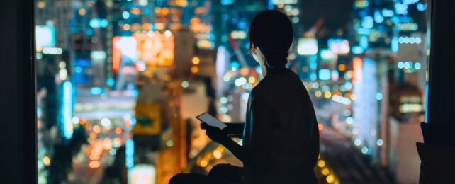 Person in darkness looking at city lights