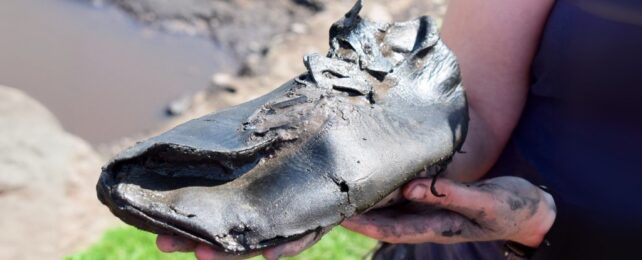 A large ancient shoe in a person's hand