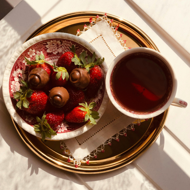 Tea in a cup next to berries and chocolate
